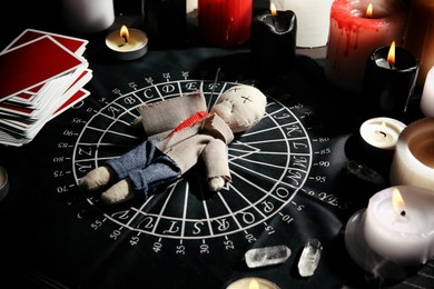 Photo of Voodoo doll pierced with needle surrounded by ceremonial items on table