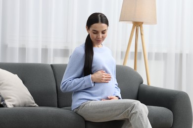 Photo of Pregnant young woman on sofa at home