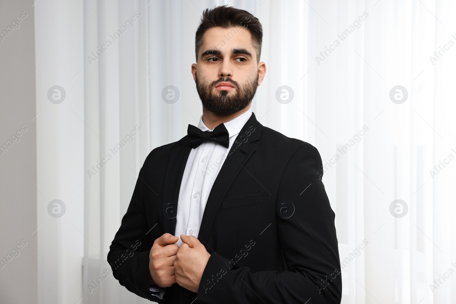 Photo of Portrait of handsome man in suit, shirt and bow tie indoors