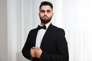 Portrait of handsome man in suit, shirt and bow tie indoors