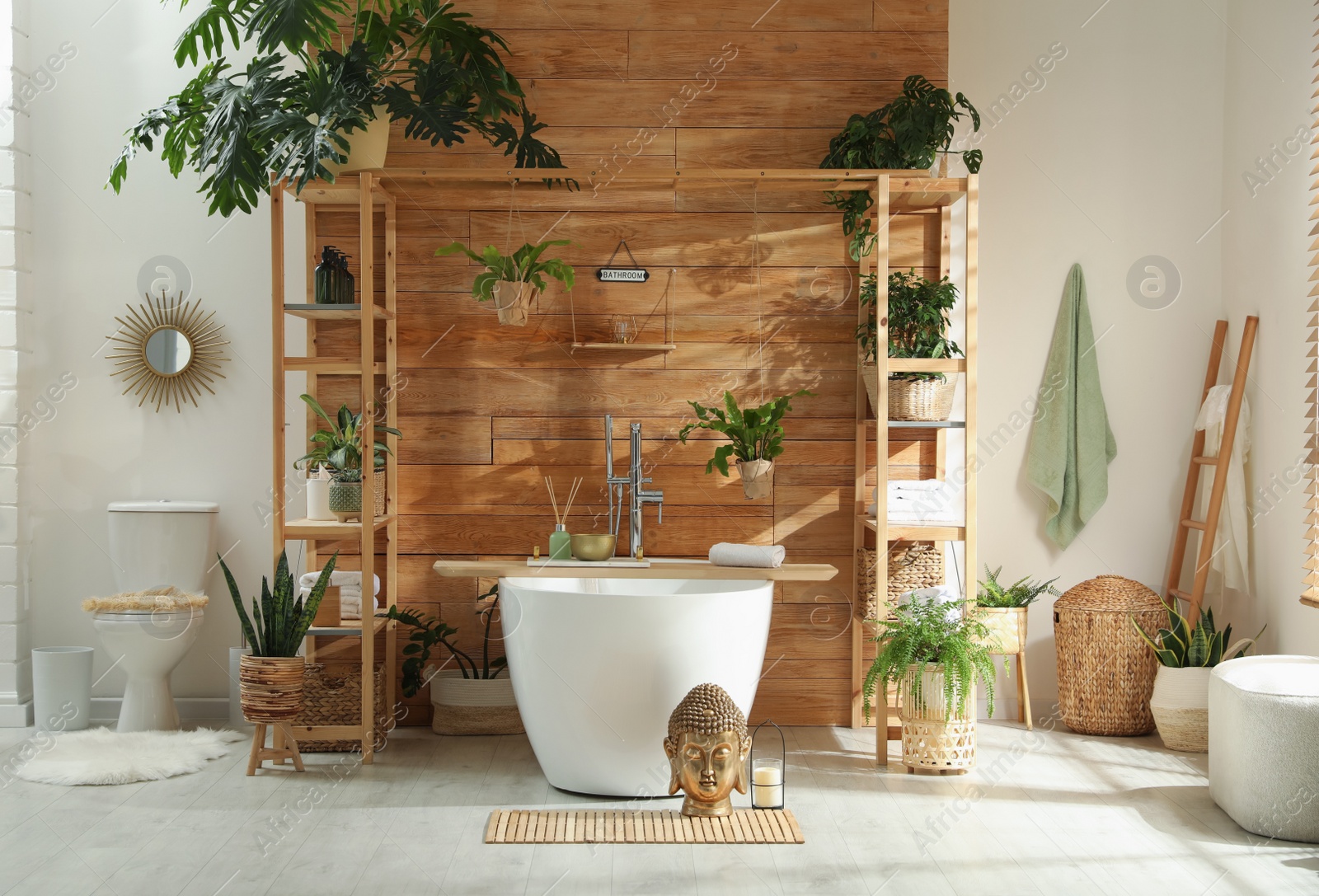 Photo of Stylish bathroom interior with white tub and green houseplants near wooden wall. Idea for design