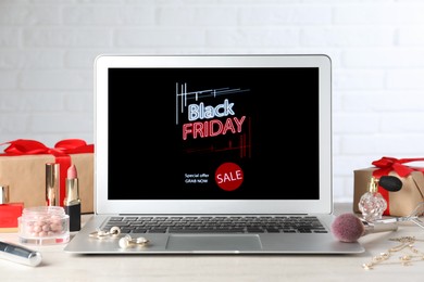 Photo of Laptop, gift boxes and women's accessories on white wooden table. Black Friday sale