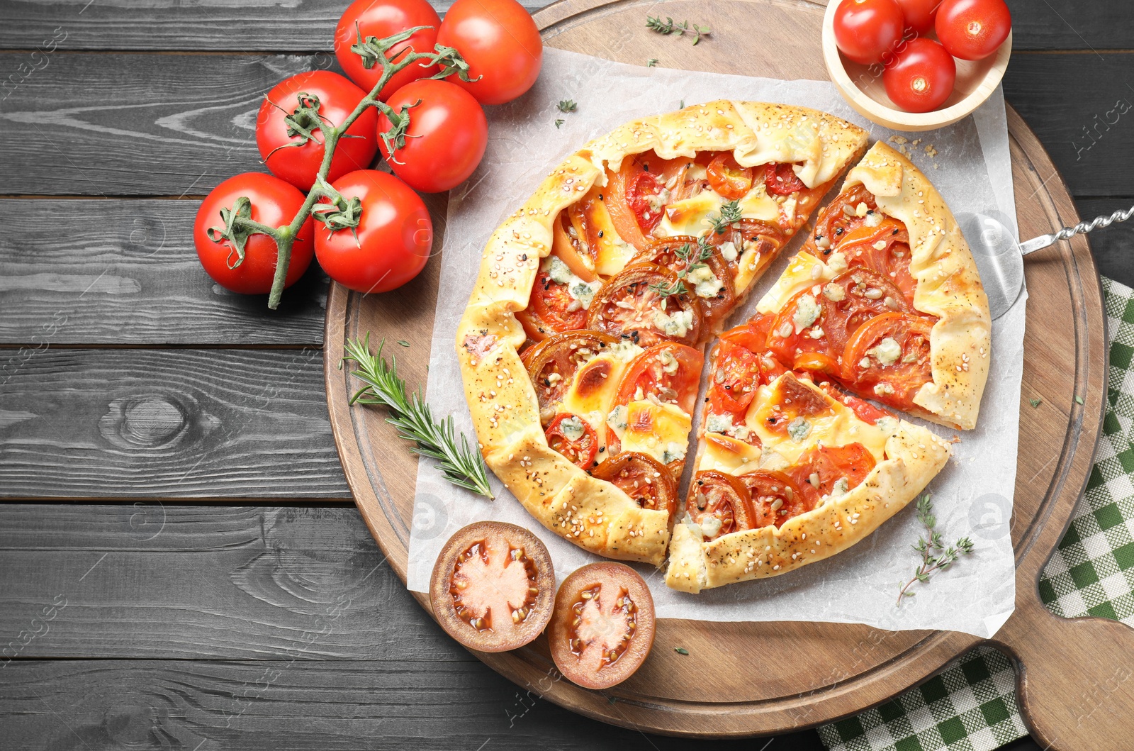 Photo of Tasty galette with tomato and cheese (Caprese galette) on black wooden table, top view. Space for text