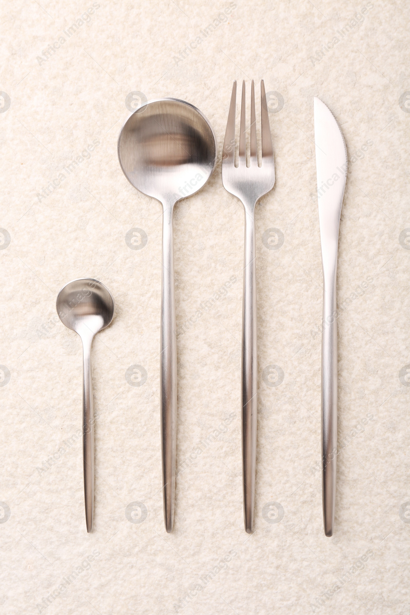 Photo of Stylish silver cutlery set on light textured table, flat lay