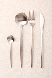 Photo of Stylish silver cutlery set on light textured table, flat lay
