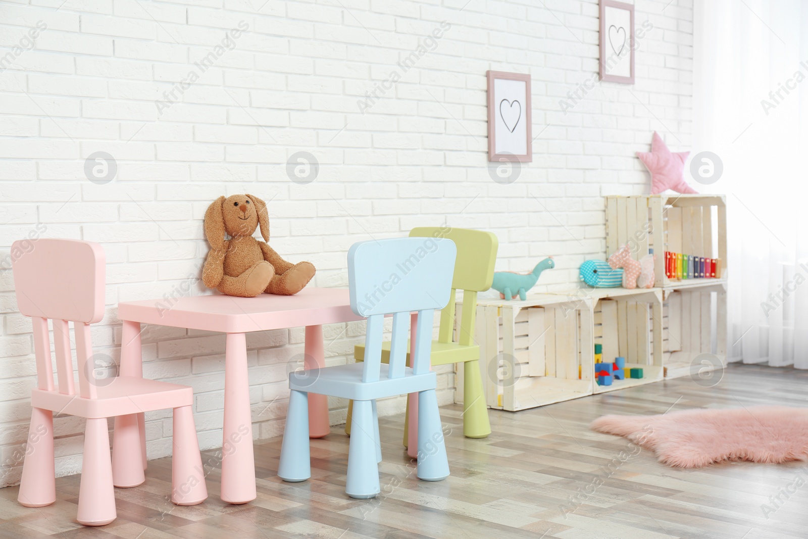 Photo of Cozy kids room interior with table, chairs and toys