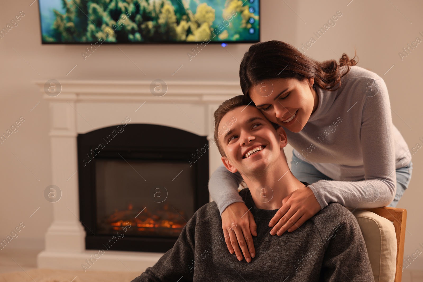 Photo of Happy lovely couple spending time together near fireplace at home