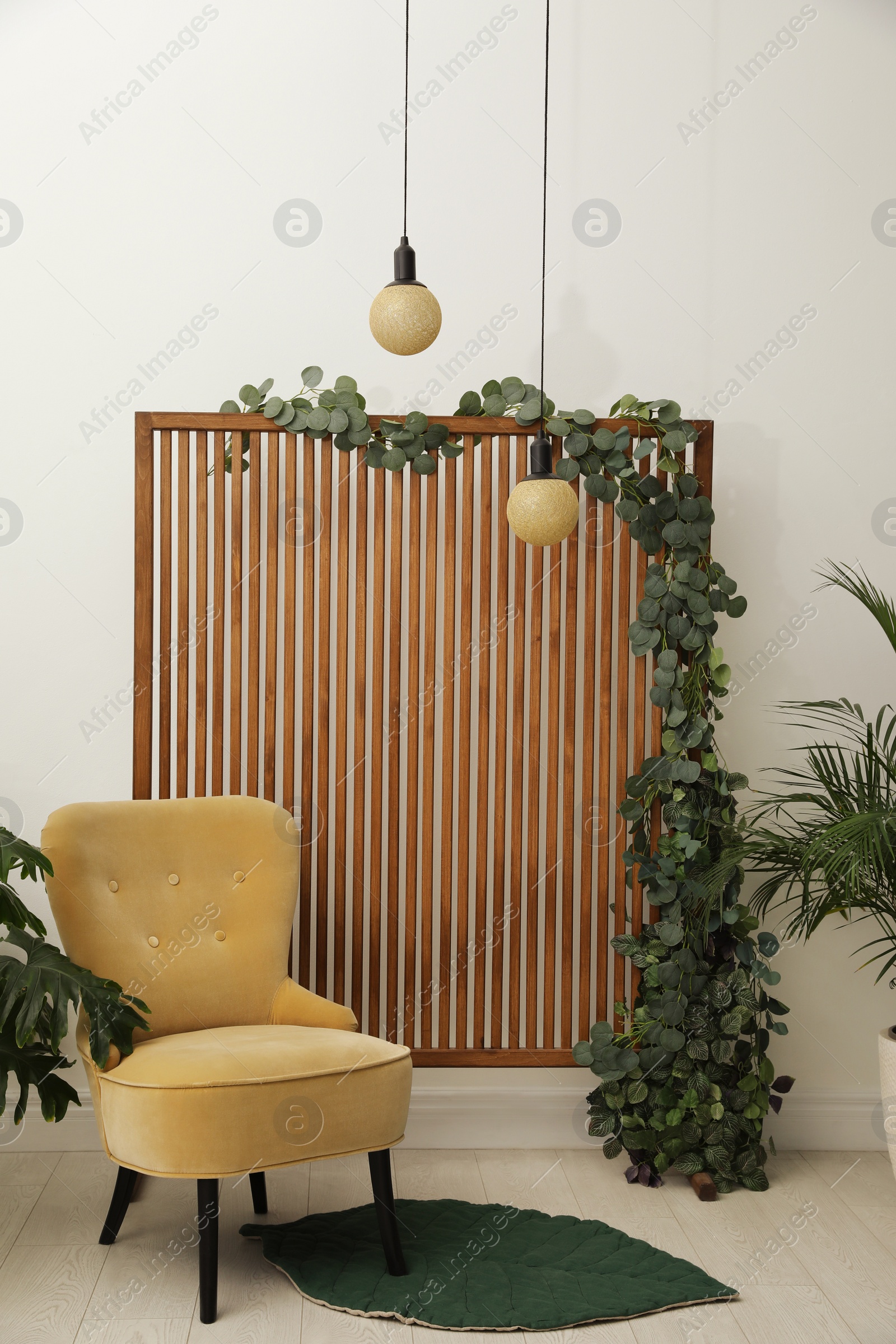 Photo of Stylish photo zone with wooden screen, floral decor and comfortable armchair indoors