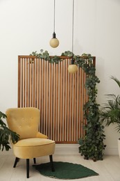 Photo of Stylish photo zone with wooden screen, floral decor and comfortable armchair indoors