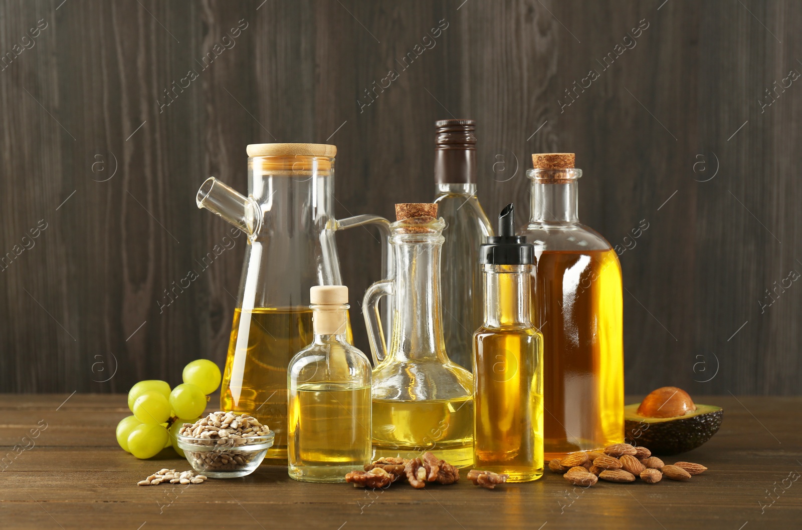 Photo of Vegetable fats. Different oils in glass bottles and ingredients on wooden table