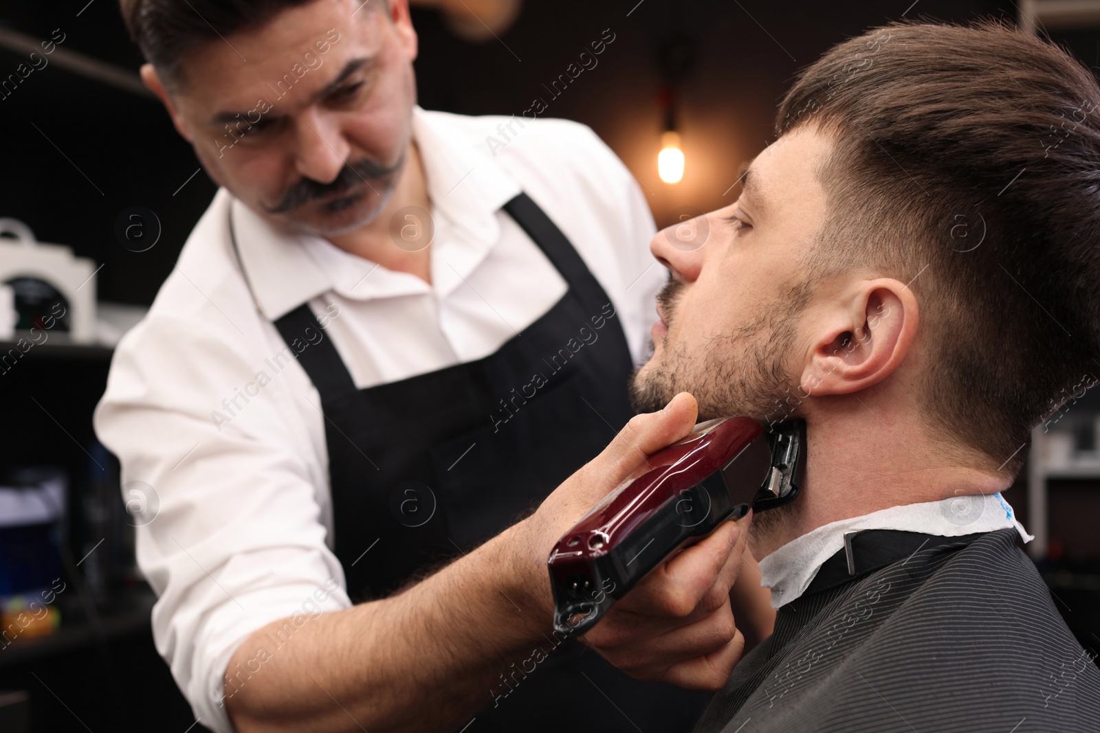 Photo of Professional hairdresser working with client in barbershop