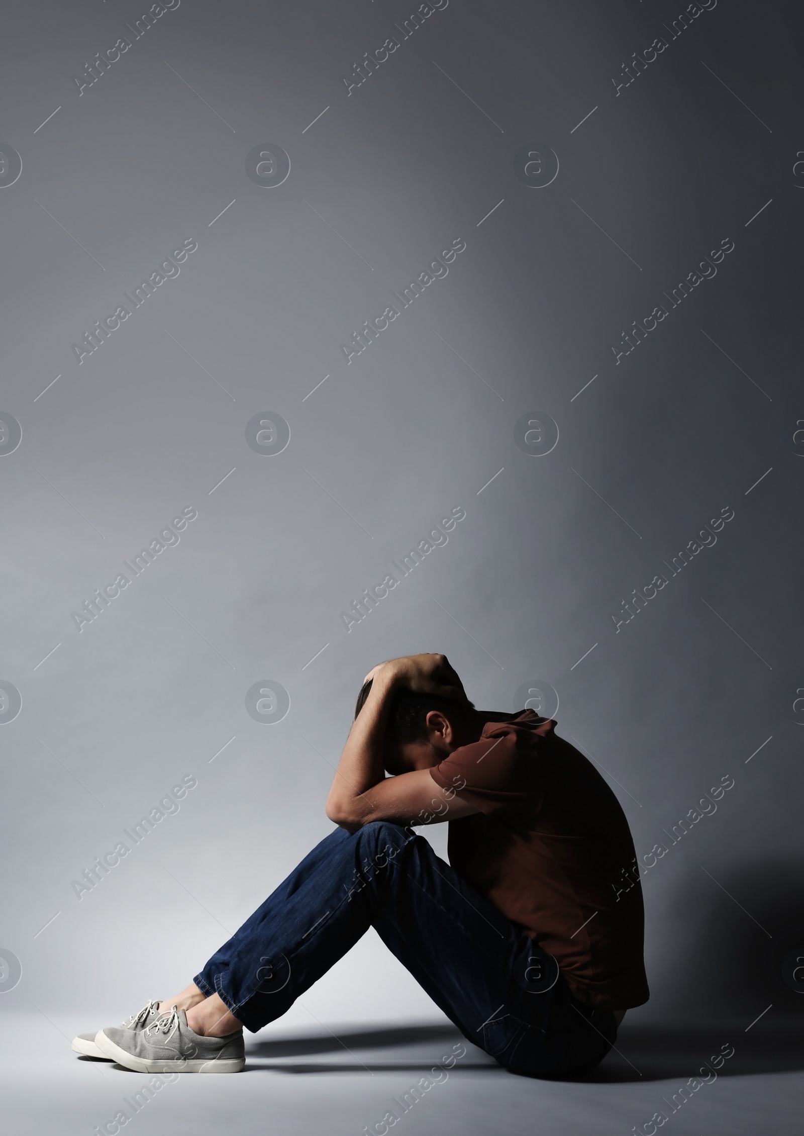 Photo of Lonely depressed man sitting on grey background
