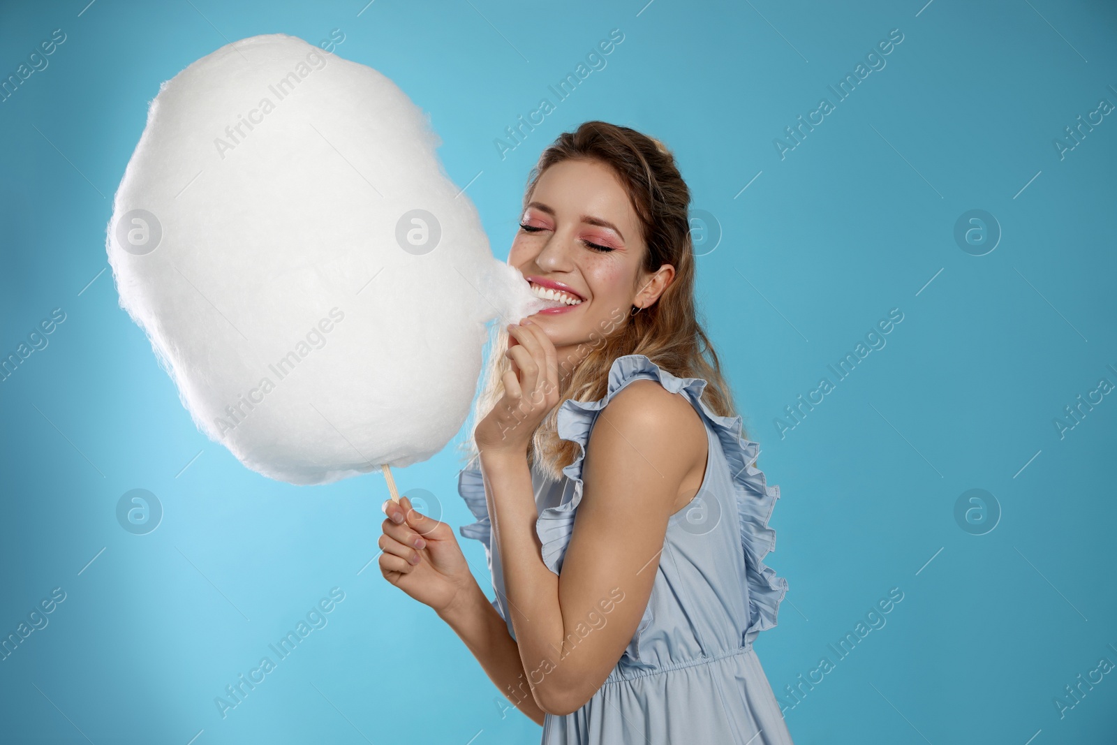 Photo of Portrait of pretty young woman with cotton candy on blue background