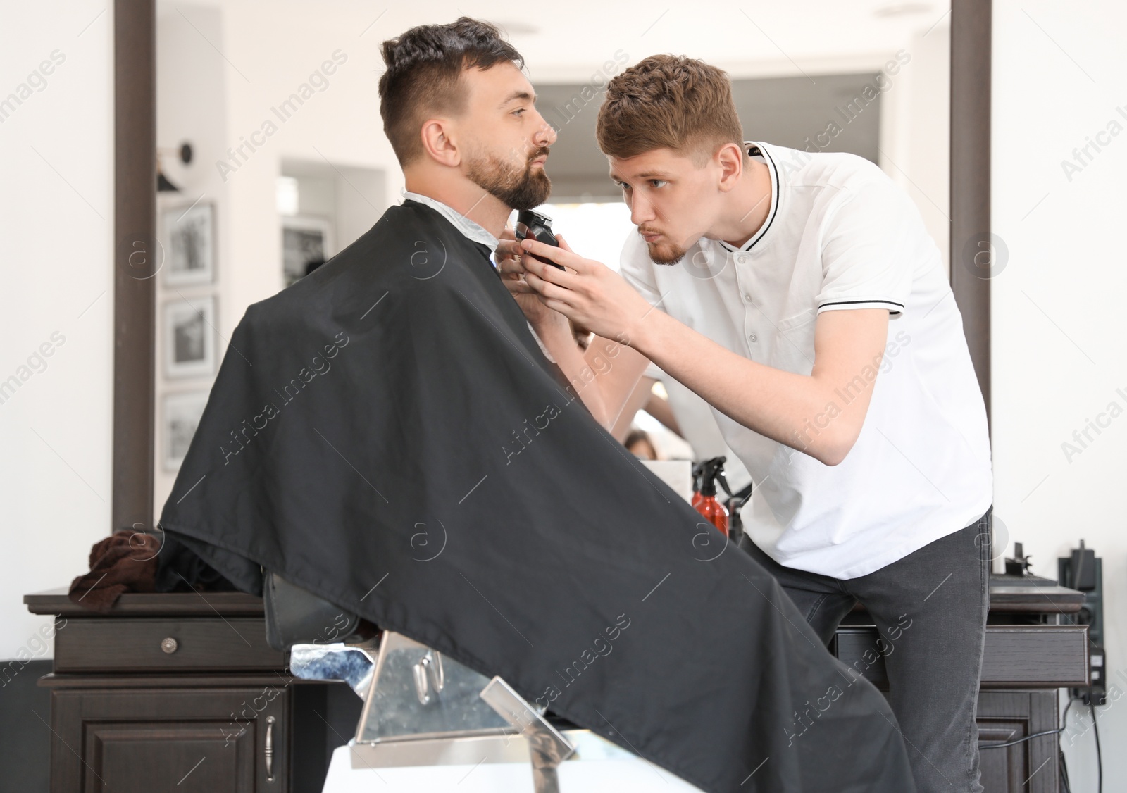 Photo of Professional barber working with client in hairdressing salon. Hipster fashion