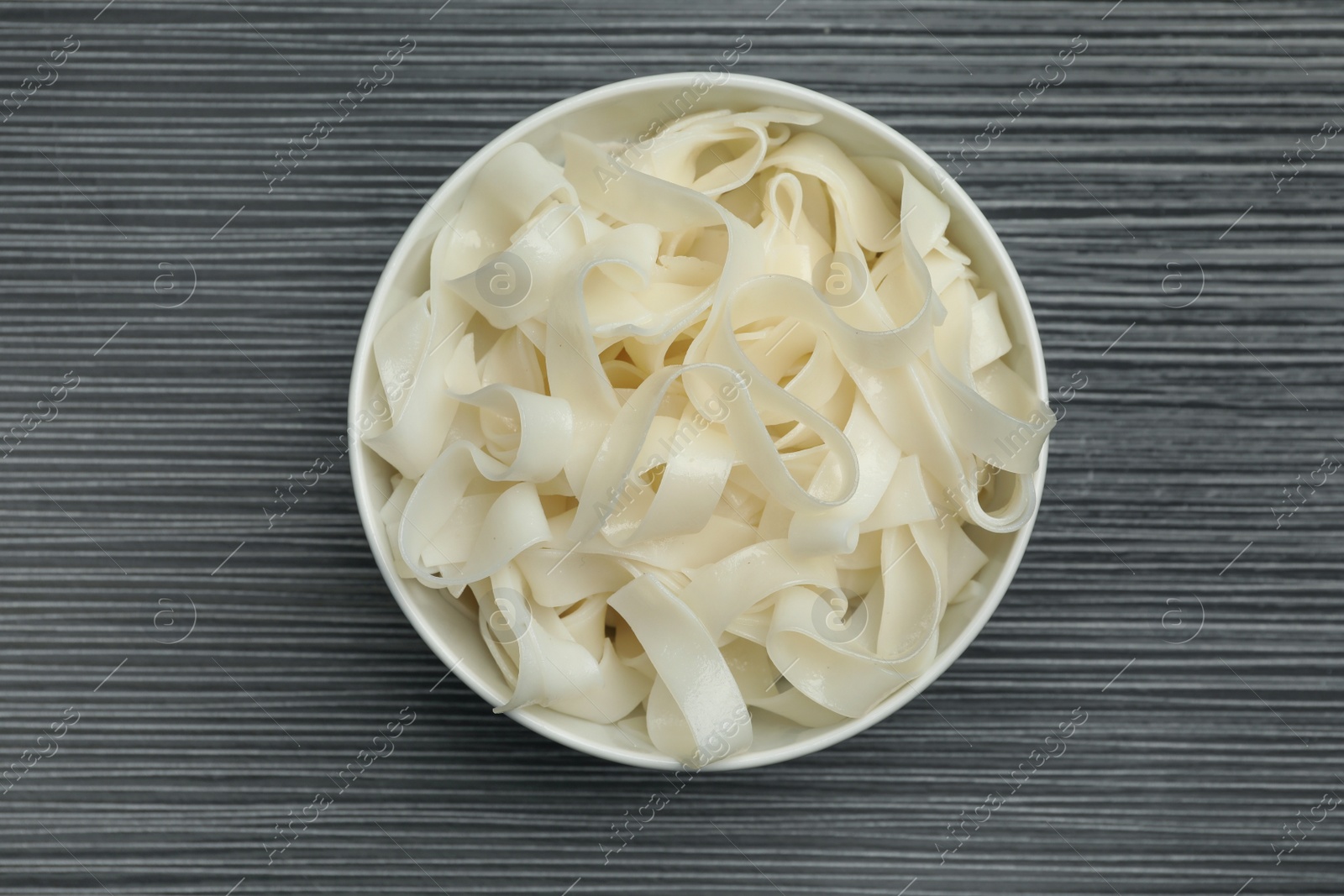 Photo of Tasty rice noodles on black wooden table, top view