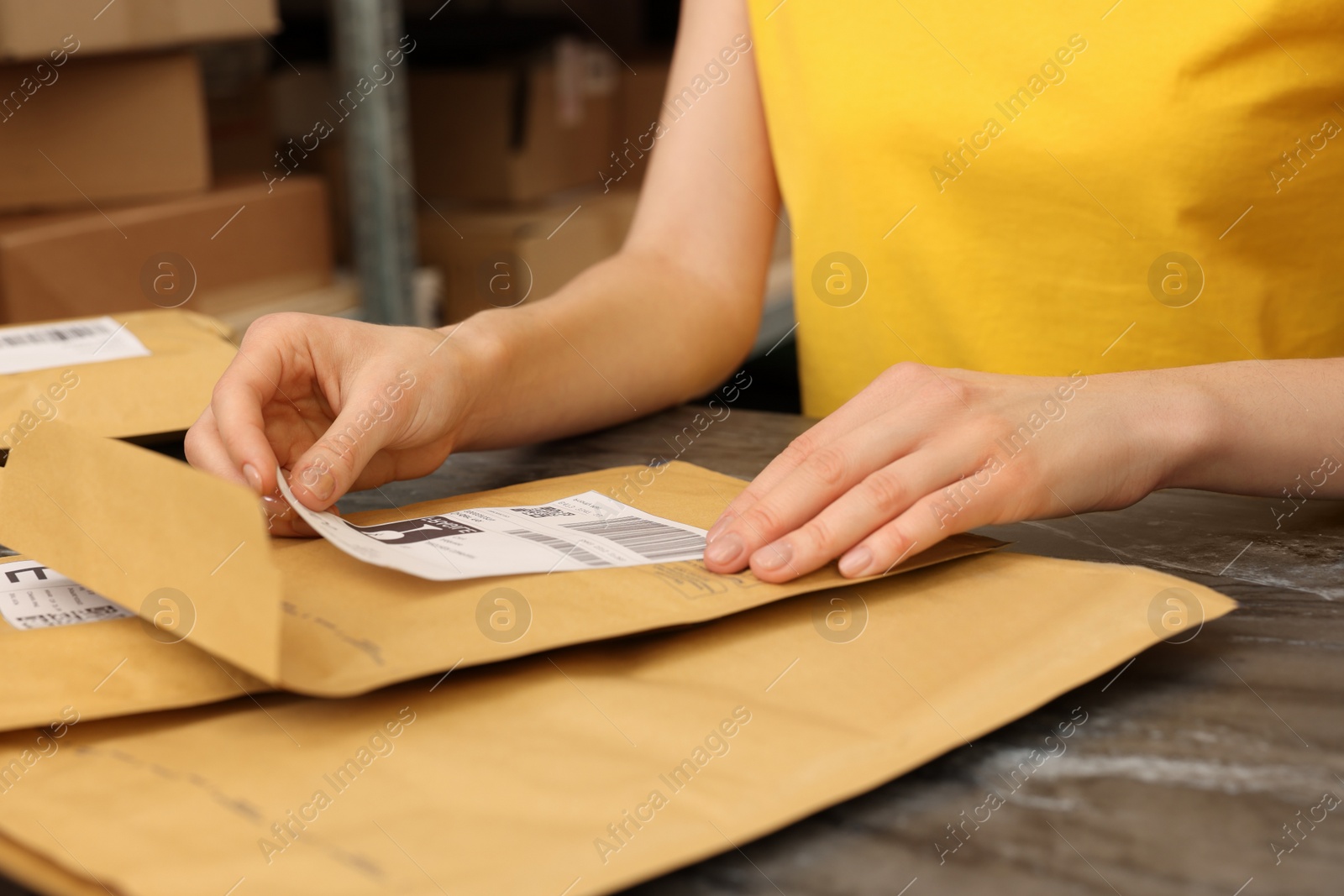 Photo of Post office worker sticking barcode on parcel at counter indoors, closeup