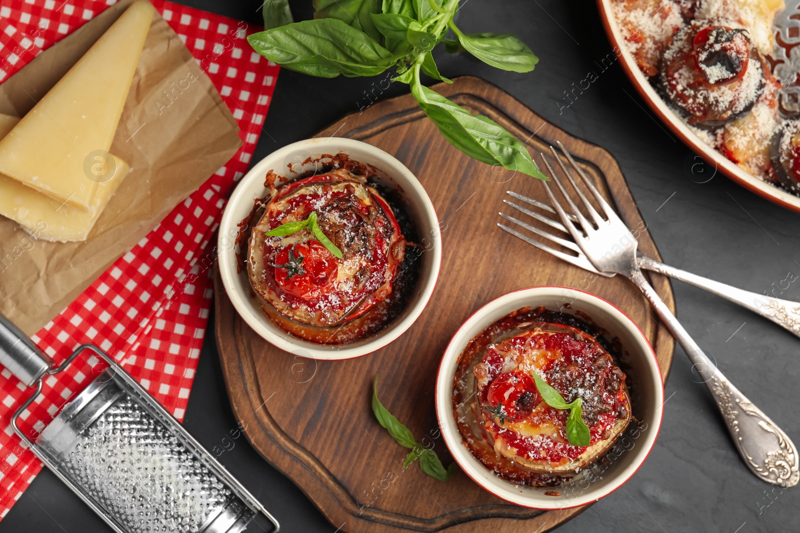 Photo of Baked eggplant with tomatoes, cheese and basil served on black table, flat lay