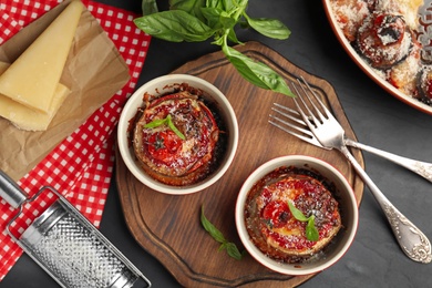 Baked eggplant with tomatoes, cheese and basil served on black table, flat lay