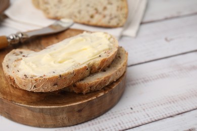 Photo of Slices of tasty bread with butter on white wooden table, closeup. Space for text