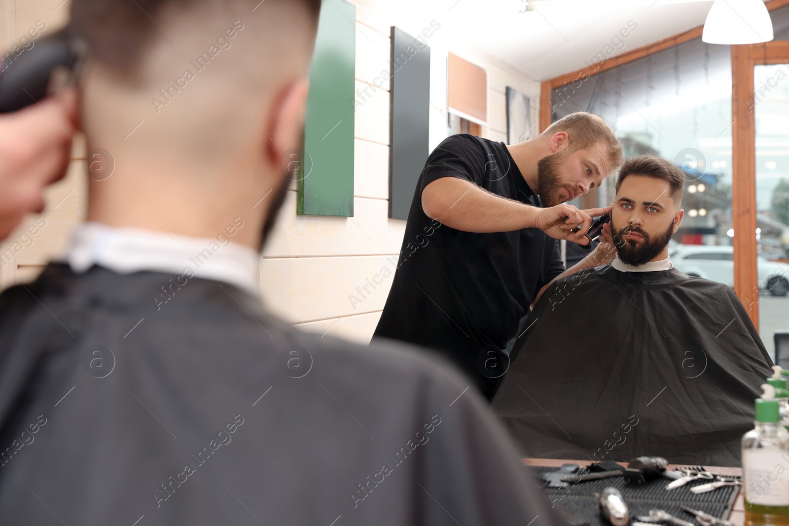 Photo of Professional hairdresser working with client in barbershop