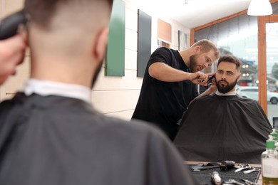 Professional hairdresser working with client in barbershop