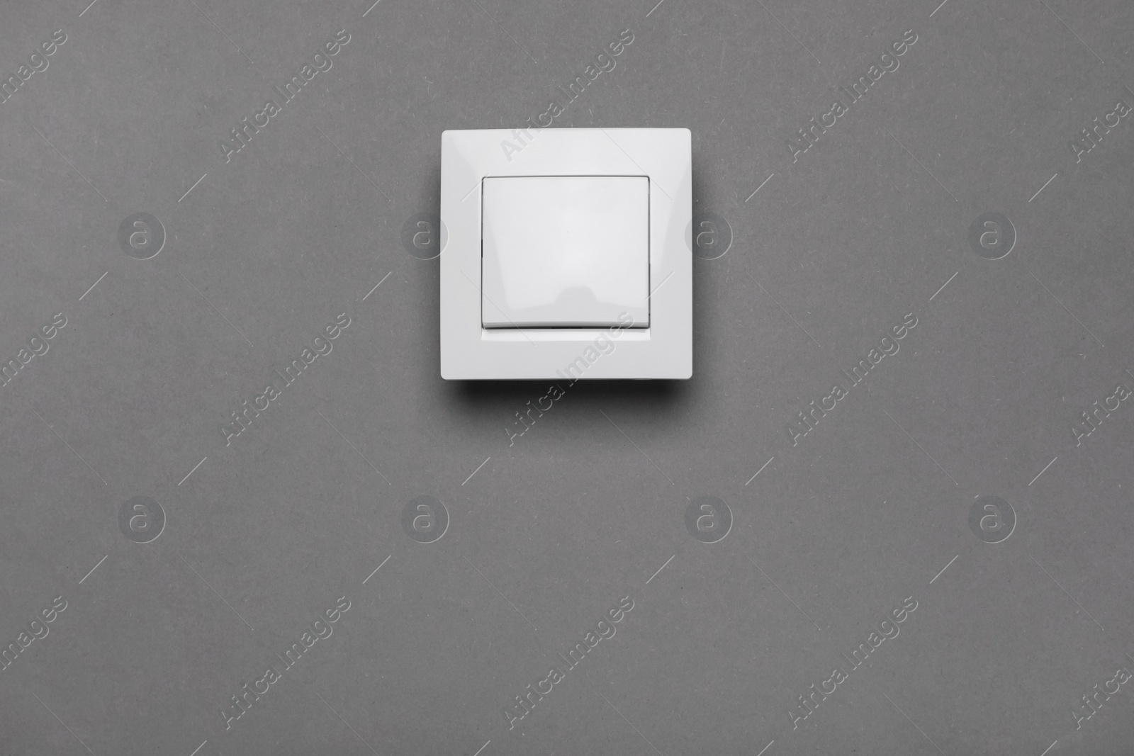 Photo of White light switch on grey background. Space for text