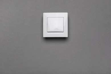 Photo of White light switch on grey background. Space for text