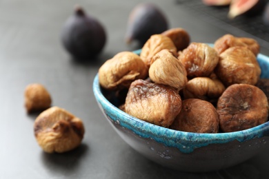 Photo of Bowl with delicious dried figs on grey table, closeup. Organic snack