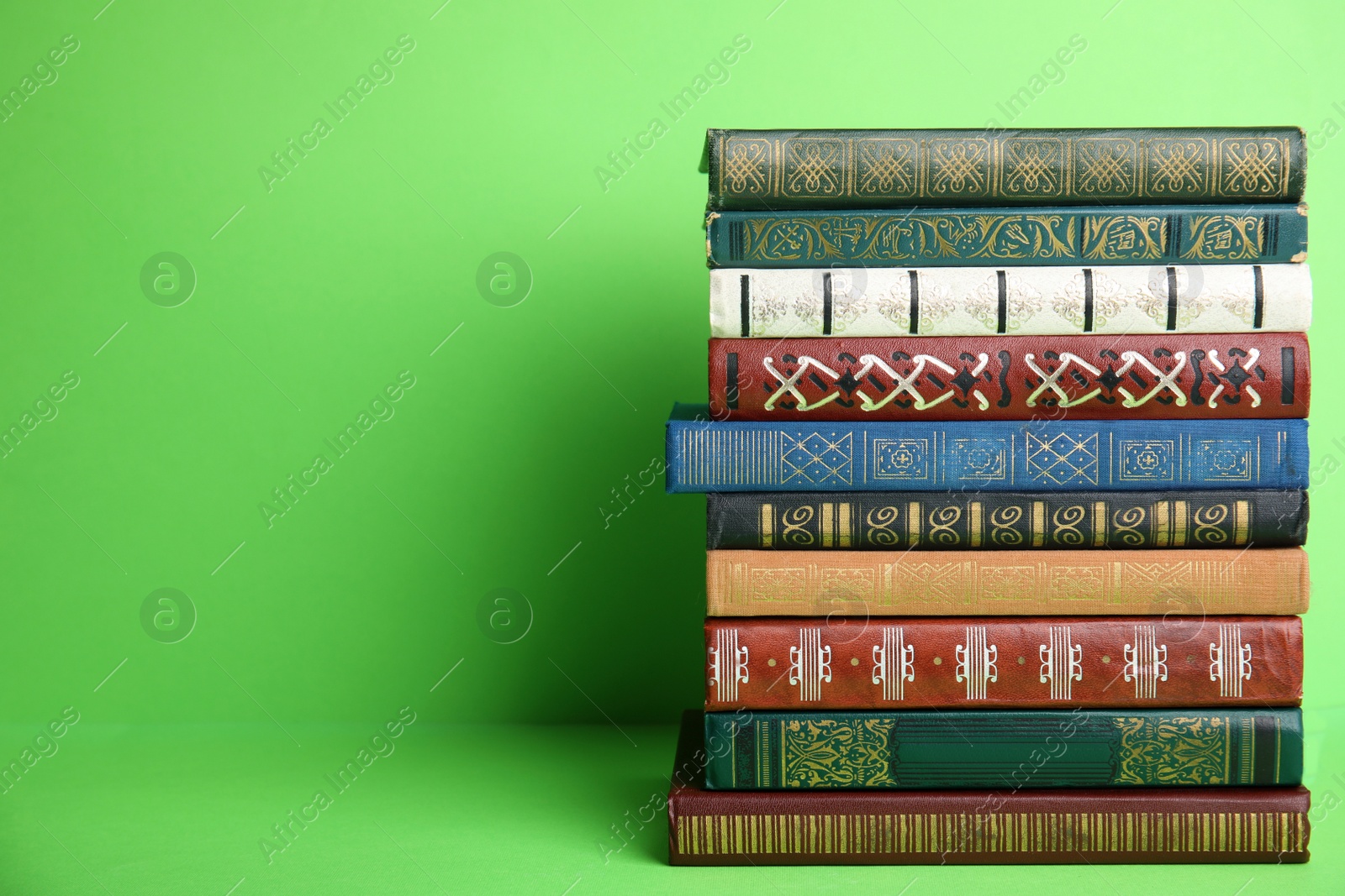 Photo of Stack of hardcover books on green background. Space for text