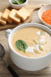 Photo of Healthy cream soup high in vegetable fats on wooden table, closeup