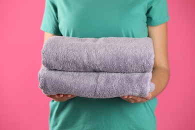 Photo of Woman holding fresh towels on pink background, closeup