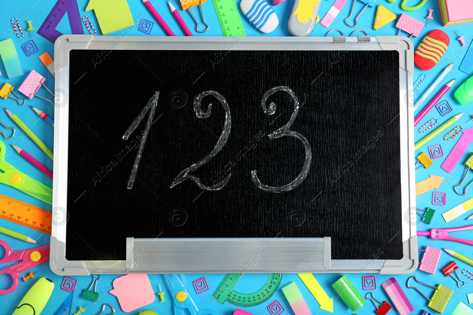 Photo of Flat lay composition with different school stationery and small chalkboard on color background