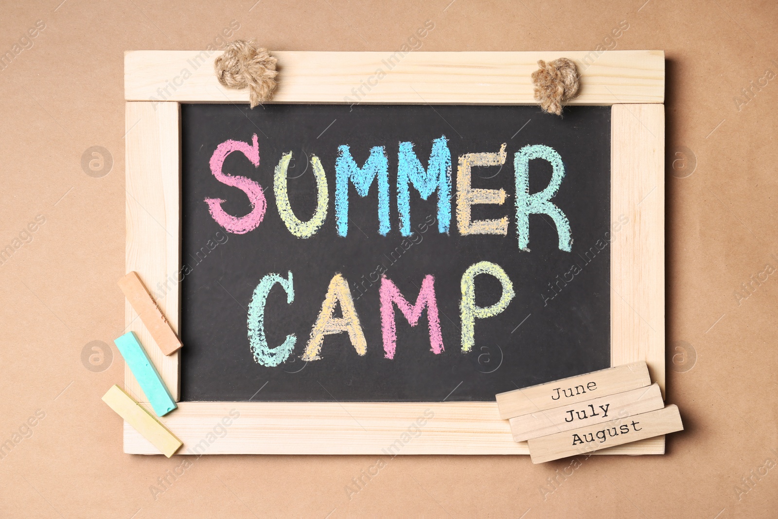 Photo of Composition with block calendar and words SUMMER CAMP written on small blackboard, top view