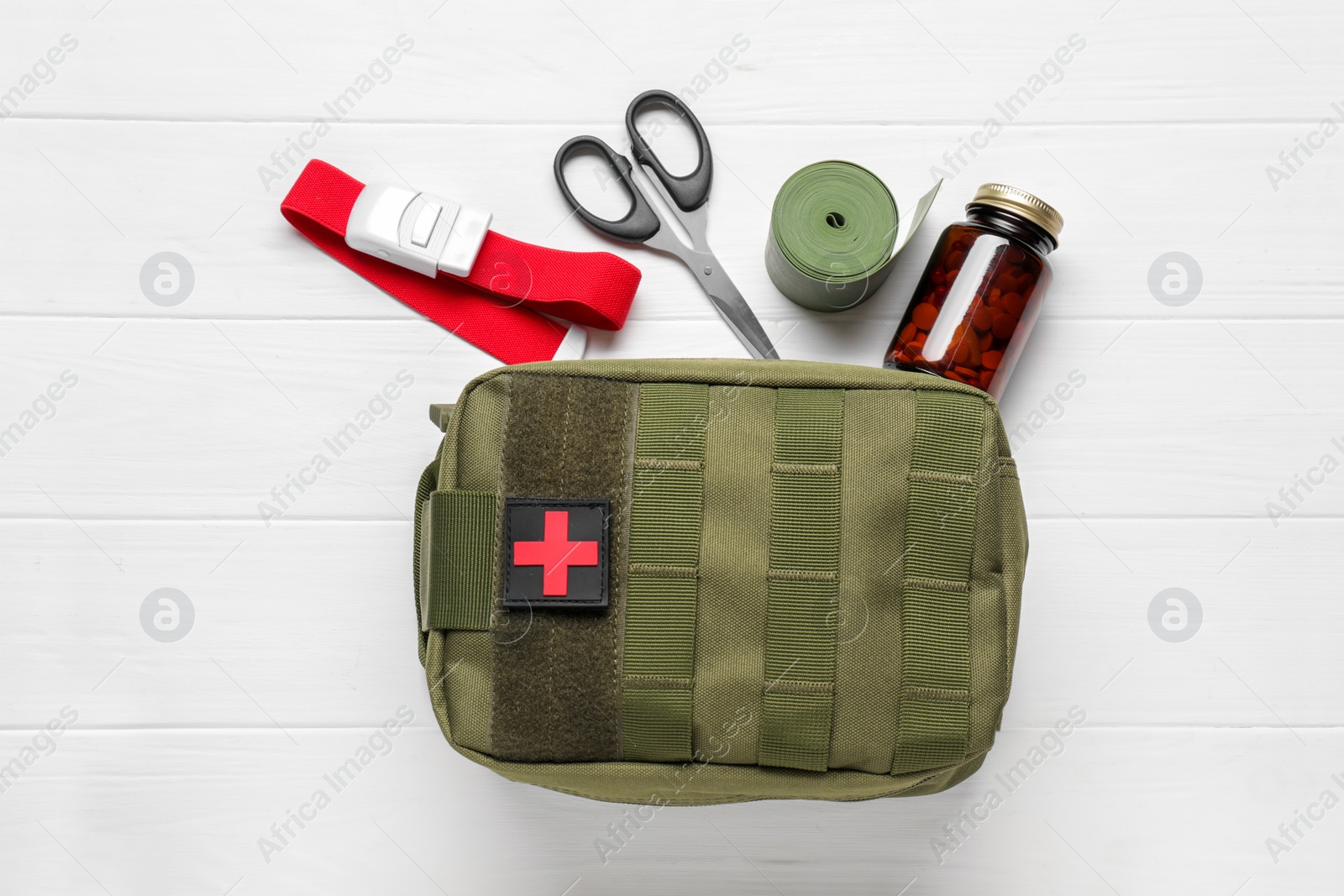 Photo of Military first aid kit, tourniquet, scissors. pills and elastic bandage on white wooden table, flat lay