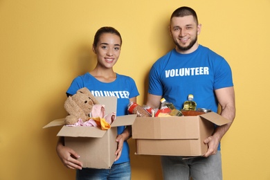 Photo of Young volunteers holding boxes with donations on color background