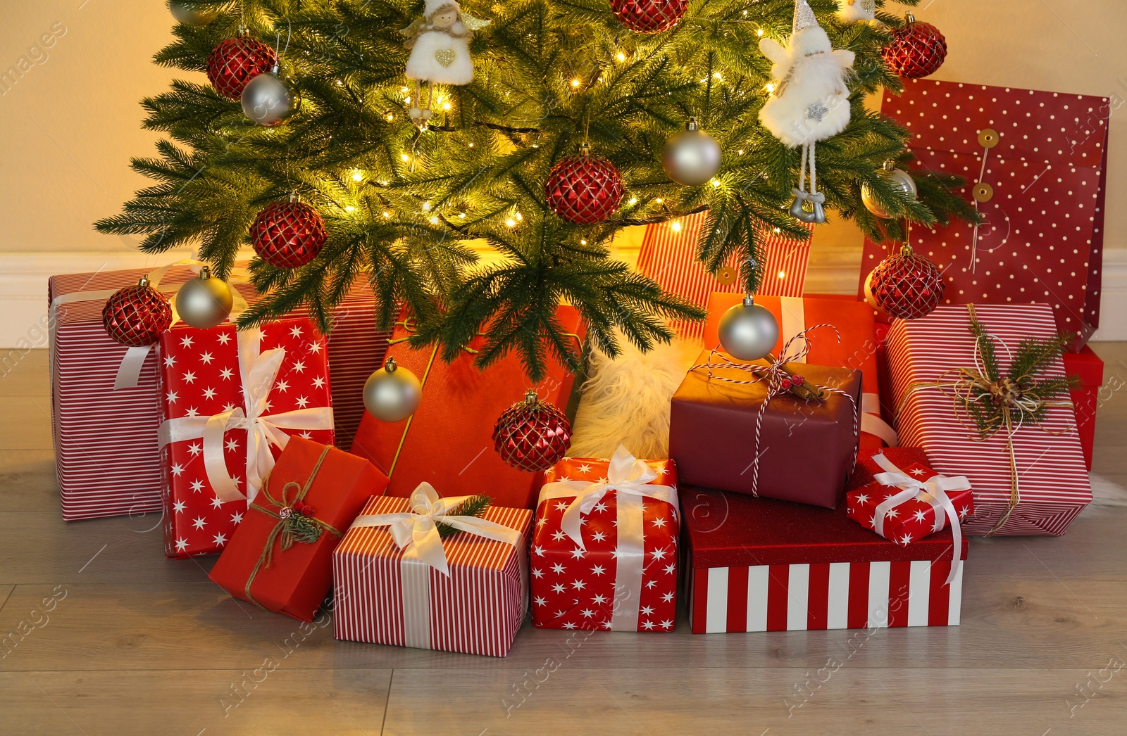 Photo of Pile of gift boxes near Christmas tree indoors