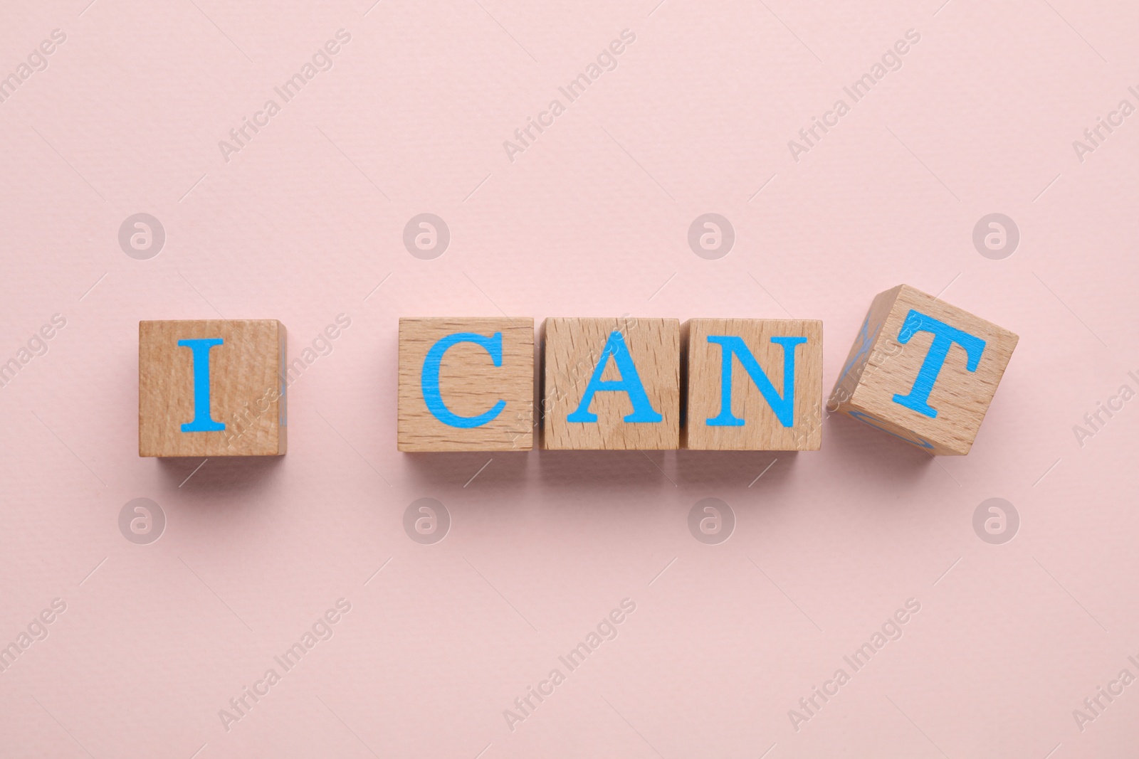 Photo of Motivation concept. Changing phrase from I Can't into I Can by removing cube with letter T on pink background, top view