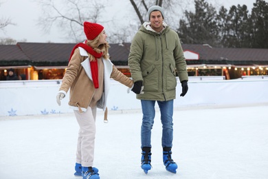 Image of Happy couple skating at outdoor ice rink