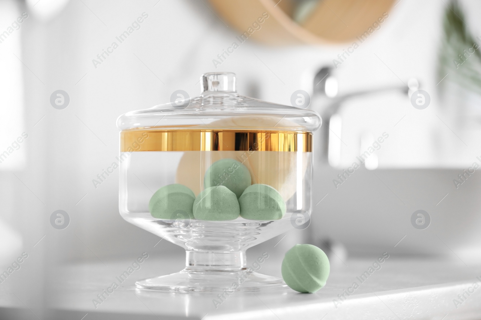 Photo of Jar with bath bombs and bath sponge on white countertop indoors