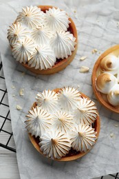 Photo of Tartlets with meringue on white wooden table, top view. Delicious dessert