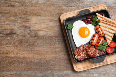 Photo of Delicious breakfast with heart shaped fried egg and  sausages on wooden table, top view. Space for text