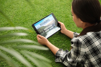 Photo of Woman booking tickets online on green grass. Travel agency concept