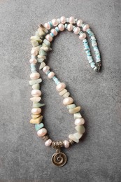 Photo of Beautiful necklace with different gemstones on grey background, top view