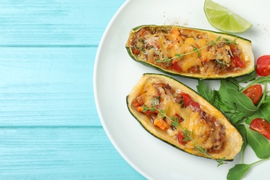 Photo of Delicious stuffed zucchini on light blue wooden table, top view. Space for text