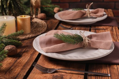 Festive place setting with beautiful dishware, cutlery and fabric napkin for Christmas dinner on wooden table