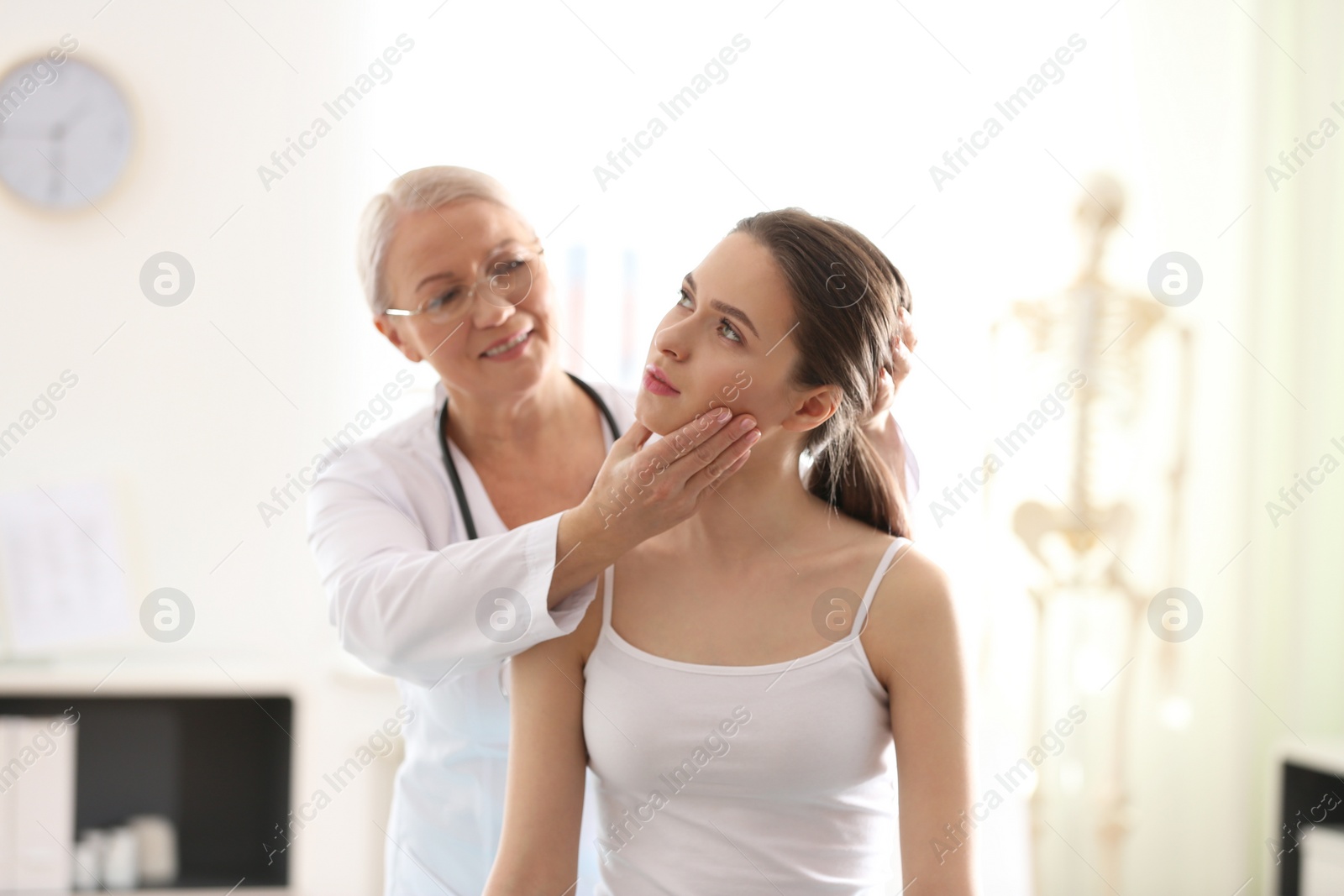 Photo of Female orthopedist examining patient's neck in clinic