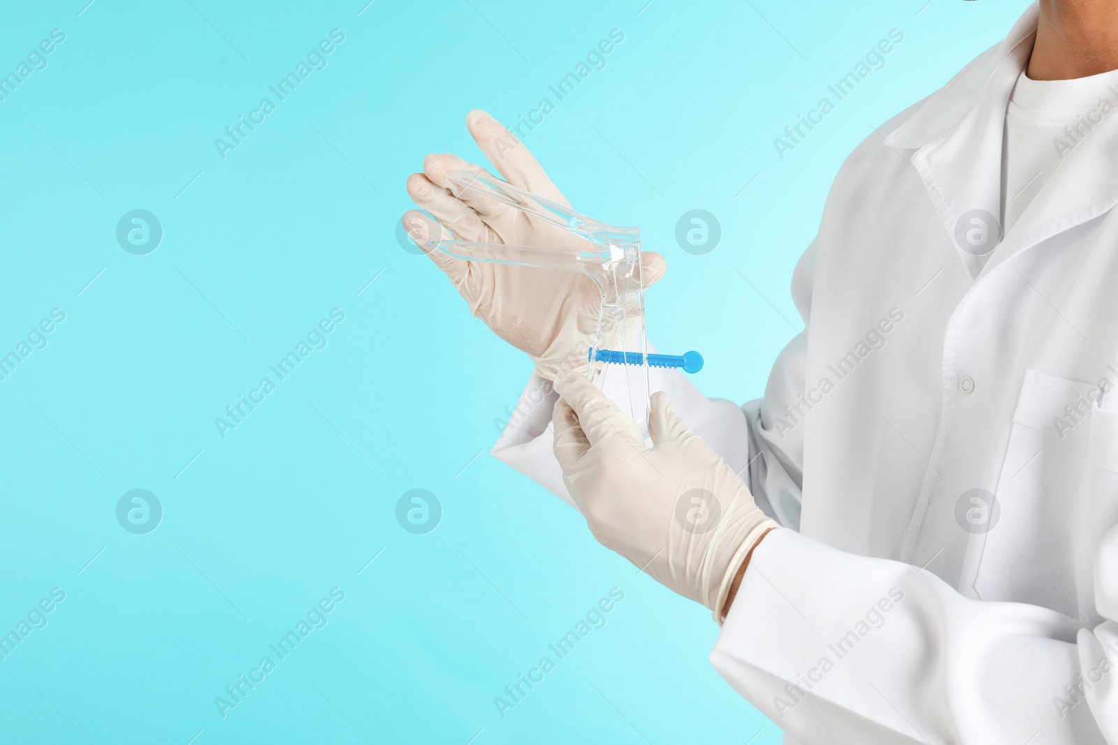 Photo of Male doctor holding disposable speculum on color background, closeup with space for text. Medical object