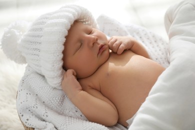 Photo of Cute newborn baby in warm hat sleeping on knitted blanket, closeup