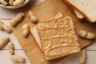 Photo of Delicious toasts with peanut butter and nuts on light wooden table, flat lay