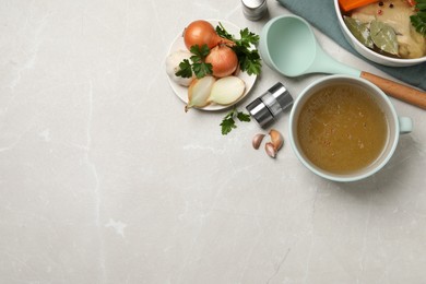 Hot delicious bouillon and ingredients on light grey table, flat lay. Space for text